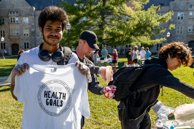 Student holding a tshirt with the words "Health Goals" written on it.